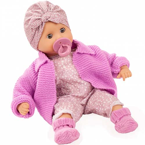 Götz babypop Muffin Soft Mood met roze gebreid vestje, stippenpakje en bijpassende hoofdband, liggend met speen in de mond.