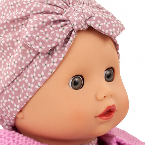 Close-up van het gezicht van de Götz babypop Muffin Soft Mood met roze stippenhoofdband.