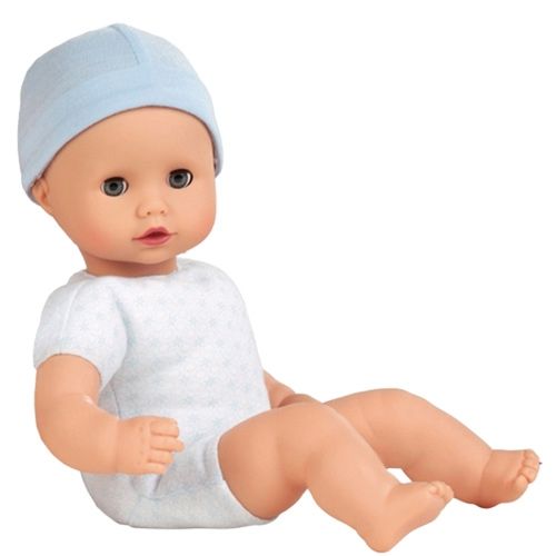 Götz babypop met lichtblauwe muts en wit pakje zit.