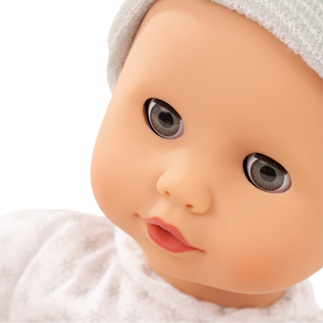 Close-up van het gezicht van de babypop met mintgroene muts.