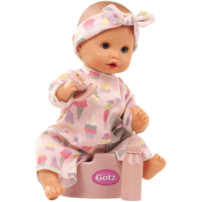 Götz bad- en plaspop met roze outfit met ijsjespatroon zit op een roze potje met een flesje ernaast.