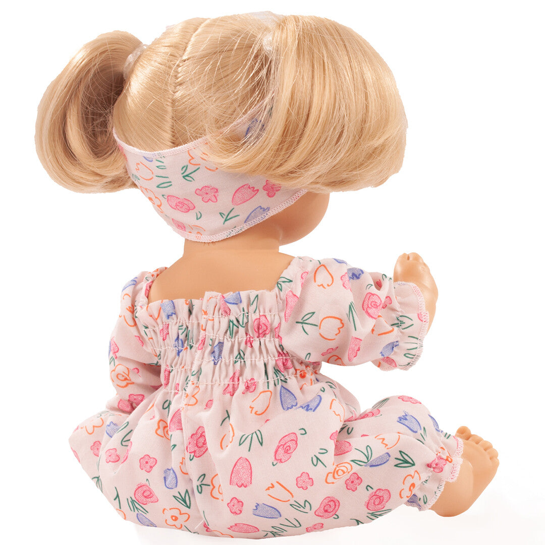 Achterkant van de badpop met blond haar in staartjes en roze gebloemde outfit.