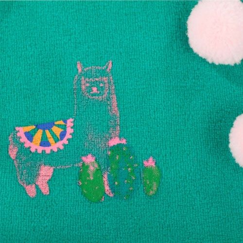 Detail van de groene overslagtop van het poppenpakje met een alpaca- en cactusprint.