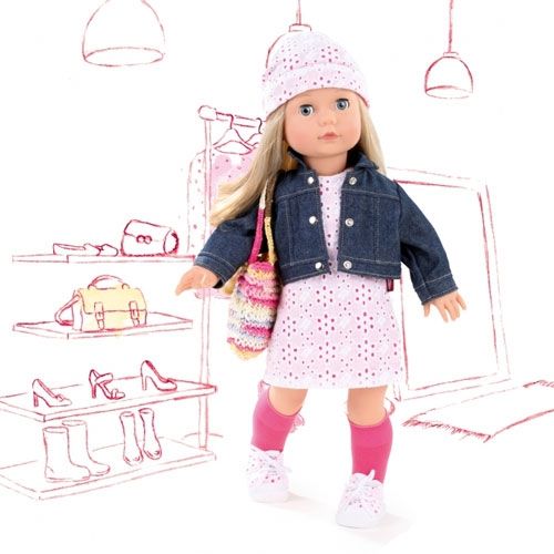 Gotz stapop Jessica staat in een roze jurk en denim jasje voor een getekende winkelachtergrond.