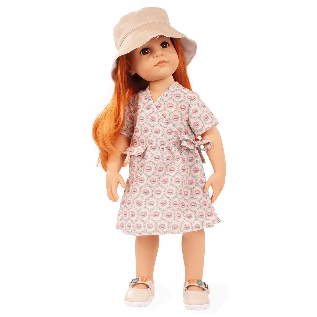 Pop met rood haar draagt de Gotz poppenkleding set met gebloemde jurk, beige hoed en schoenen.