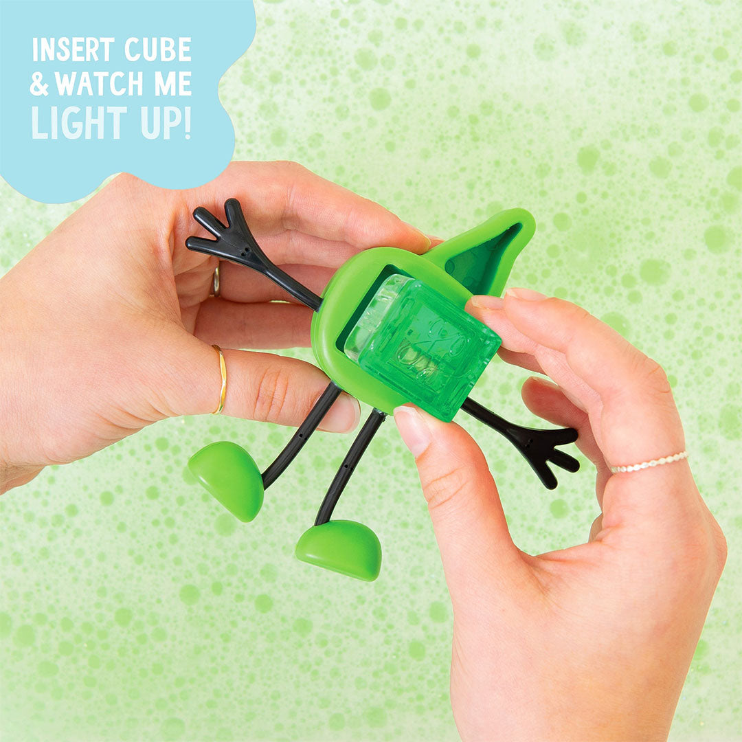 Handen plaatsen een lichtgevend blokje in de achterkant van het Glo Pals groene badspeelgoed figuurtje.