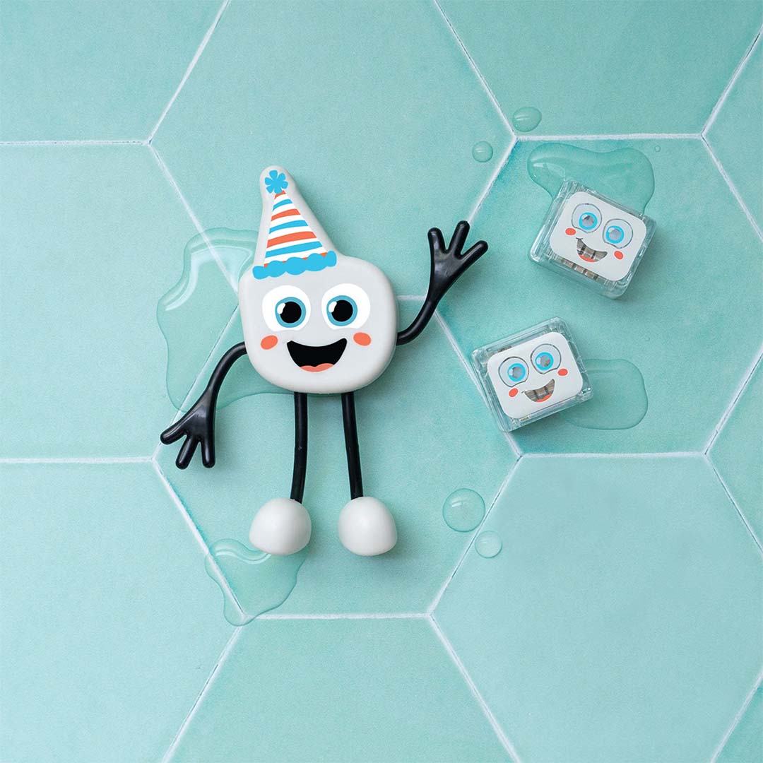 Glo Pals Party Pal badspeelgoedfiguur en twee lichtblokjes liggen op een turquoise tegelvloer.