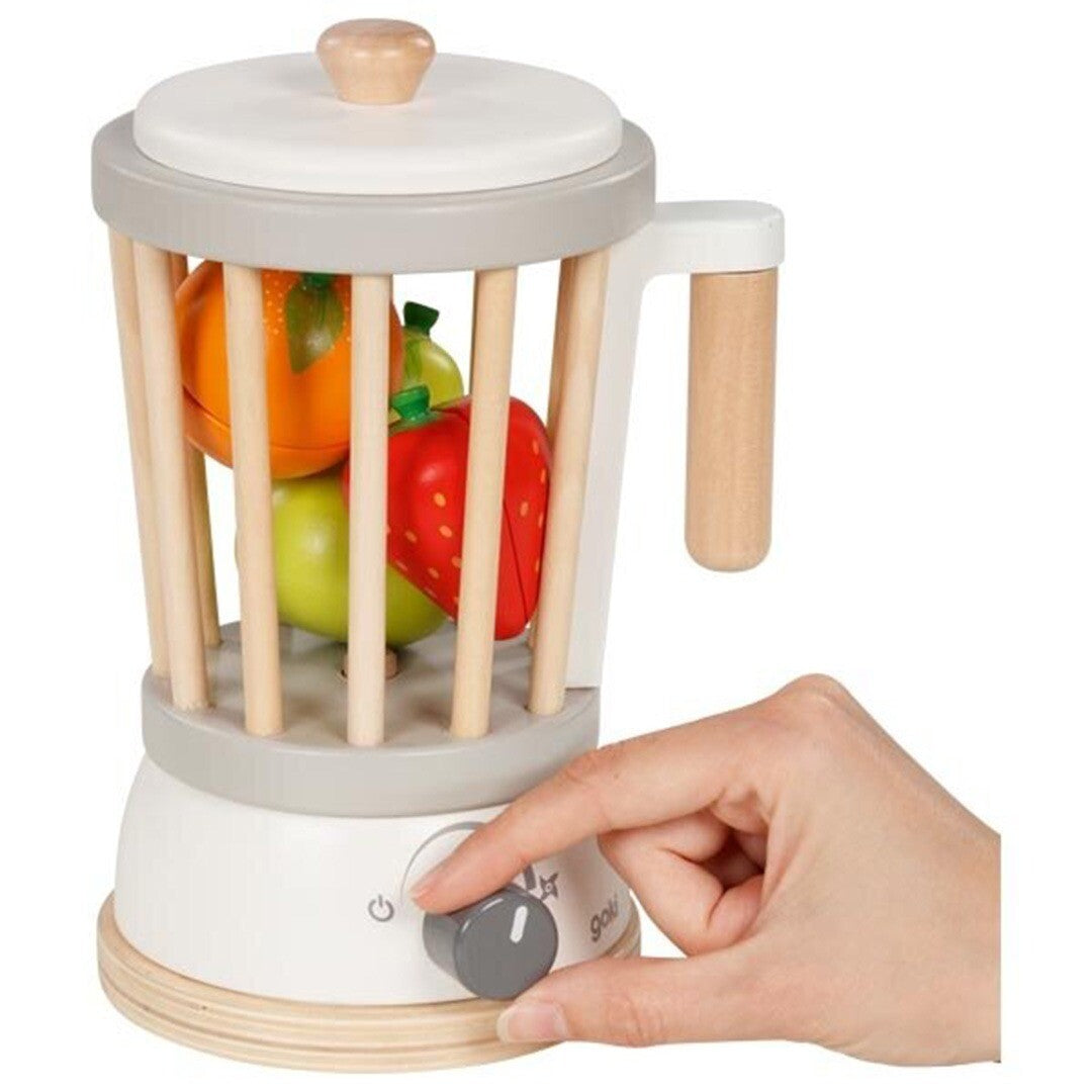 Een hand draait aan de knop van de goki houten speelgoedblender met fruit.