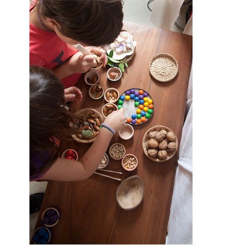 Twee kinderen spelen met het Grapat sorteerspeelgoed met gekleurde houten knikkers en natuurlijke materialen.
