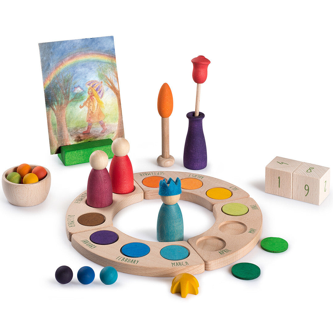 Een Grapat eeuwige kalender van hout met gekleurde poppetjes, boomvormen, een vaas, een regenboogtekening en houten dobbelstenen.