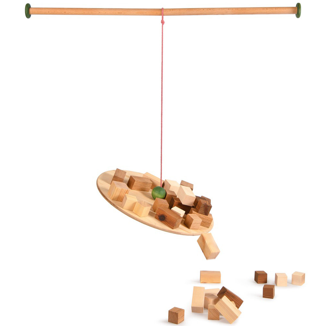 Grapat balansbord met houten blokken en een groene bal, deels van het bord gevallen.