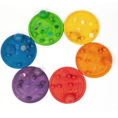 Zes houten sorteerplaten in regenboogkleuren, elk gevuld met kleine voorwerpen in dezelfde kleur.