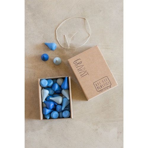 De verpakking van Grapat houten druppels in blauwtinten, met een open doos vol druppels en een touwtje ernaast.