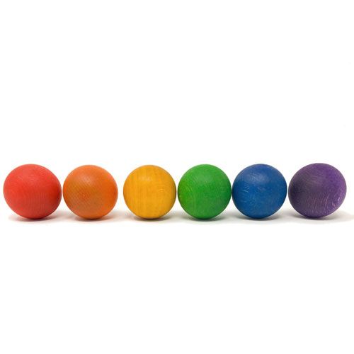 Grapat babyspeelgoed: zes houten regenboogballen op een rij.