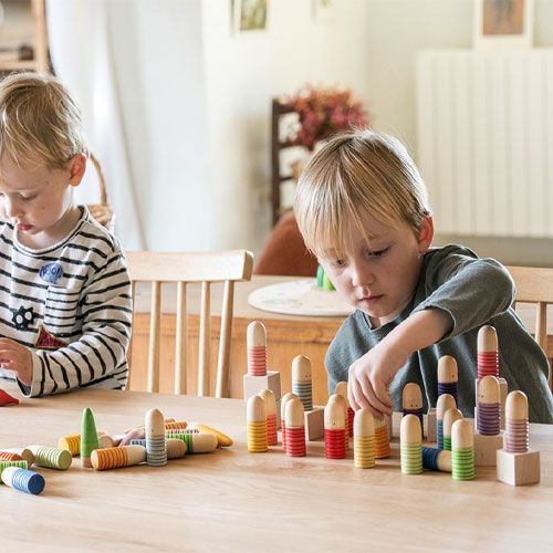 Twee jongens spelen samen met de grapat houten brots poppetjes op een tafel.