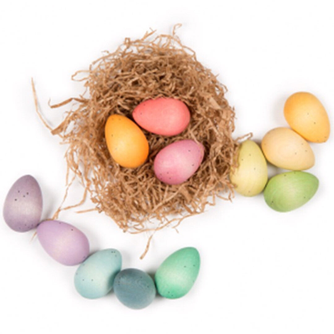 Grapat houten pastel eieren in en rondom een strooien nest op een witte achtergrond.