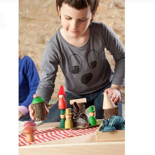 Een kind speelt met Grapat houten nins® kabouters en houten blokken op een tafel.