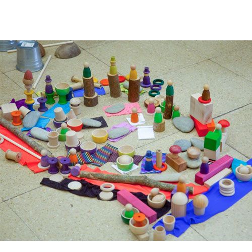 Een speelopstelling met diverse Grapat houten speelgoedstukken, waaronder Nins poppetjes, schalen en blokken.