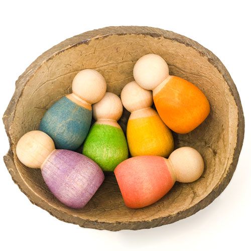 Grapat houten Nins poppetjes baby's in verschillende kleuren, liggend in een natuurlijke kom.