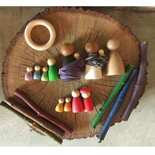 Grapat houten Nins poppetjes in verschillende maten en kleuren, met een houten ring en gekleurde takjes, op een houten schijf.