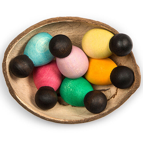 grapat houten nins® poppetjes baby's en donkere houten ballen in een kokosnootkom.