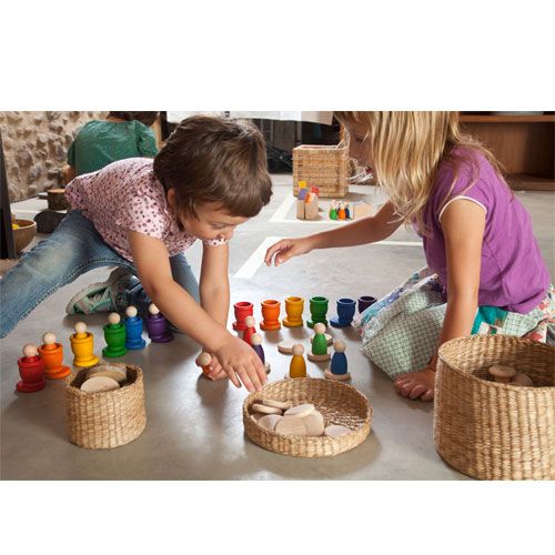 Twee kinderen spelen met het grapat houten sorteer- en stapelspeelgoed, bestaande uit nins® poppetjes, bakjes en schijfjes.