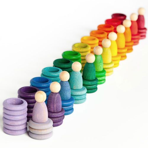 Grapat houten sorteer- en stapelspeelgoed met Nins poppetjes, ringen en schijfjes in een regenboogkleurenreeks.