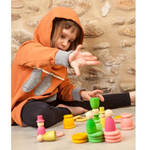 Een kind speelt met Grapat houten nins® poppetjes, ringen en schijfjes, die als sorteer- en stapelspeelgoed dienen.
