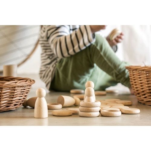 Een kind speelt met Grapat houten Nins® poppetjes, ringen en schijfjes als stapelspeelgoed op de grond.