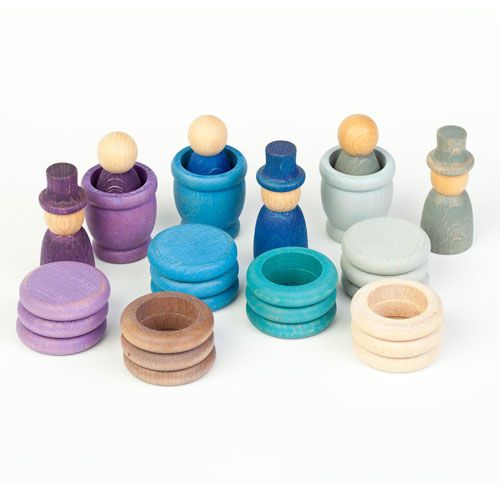 Grapat houten Nins poppetjes, ringen en schijfjes in winterkleuren liggen verspreid op een witte ondergrond.