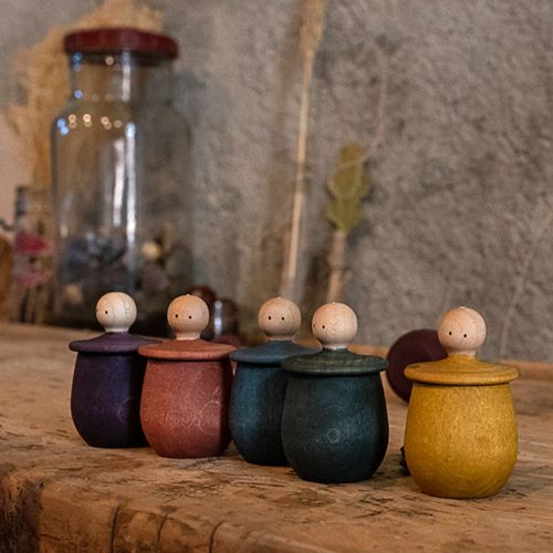 Een rij Grapat houten poppetjes in bakjes in verschillende kleuren op een houten ondergrond.