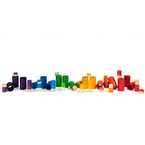 Een collectie grapat houten poppetjes en buizen in regenboogkleuren, verspreid over een witte ondergrond.