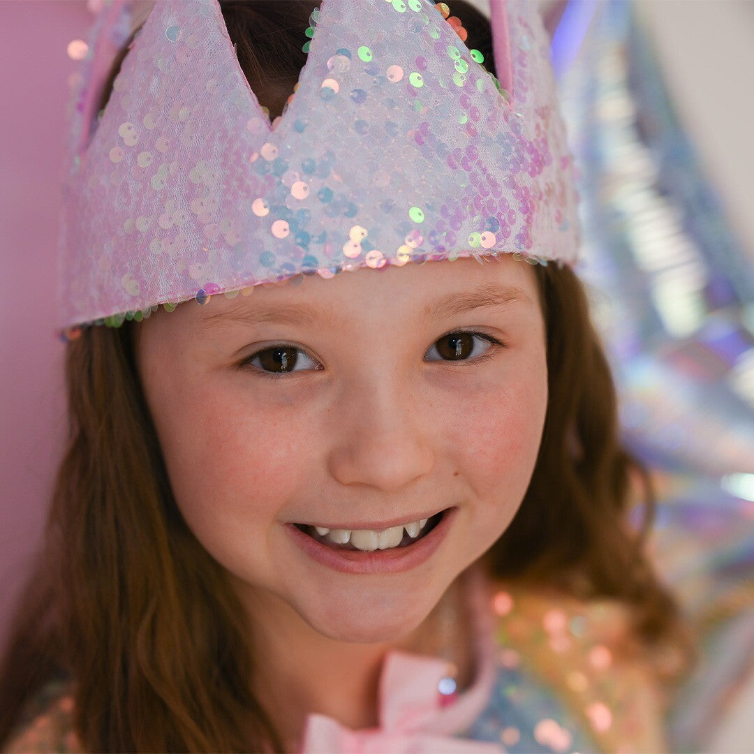 Een lachend meisje draagt de roze pailletten kinderkroon.