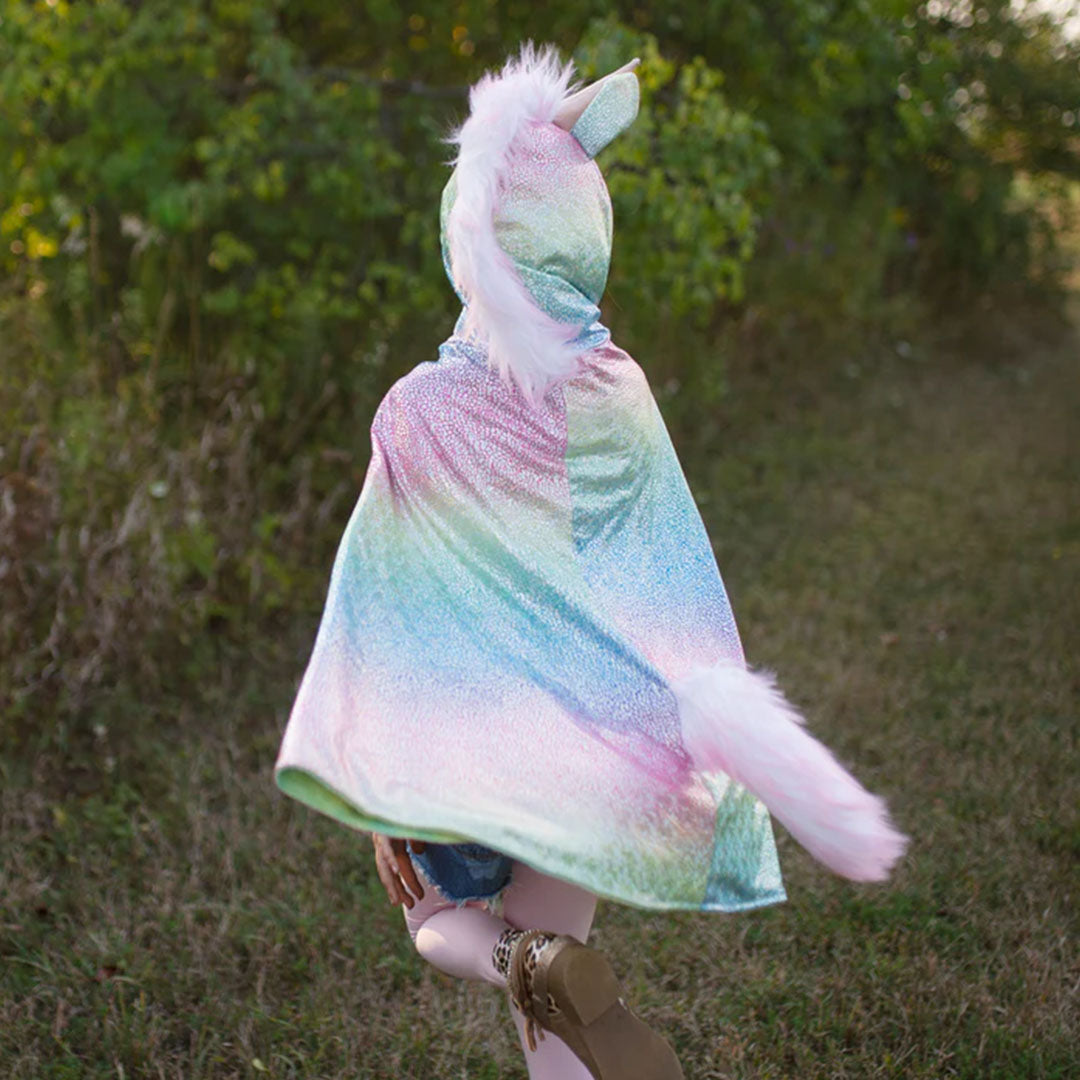 Kind van achteren gezien, rennend in een great pretenders regenboog eenhoorn verkleedcape met pluizige staart en manen.