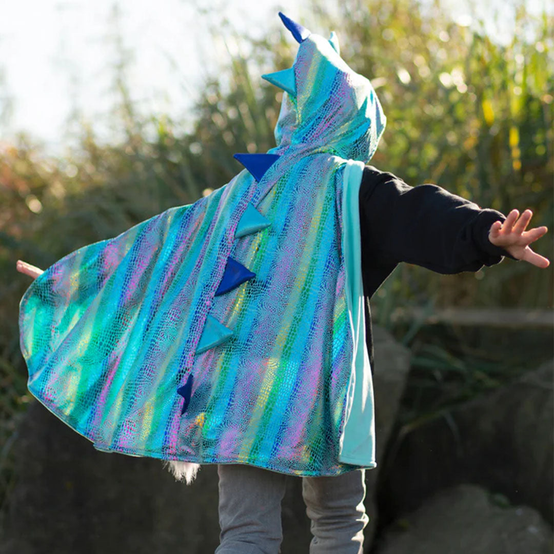 Kind draagt de great pretenders omkeerbare drakenverkleedcape met glimmende blauwe schubben en stekels, van achteren gezien buiten.