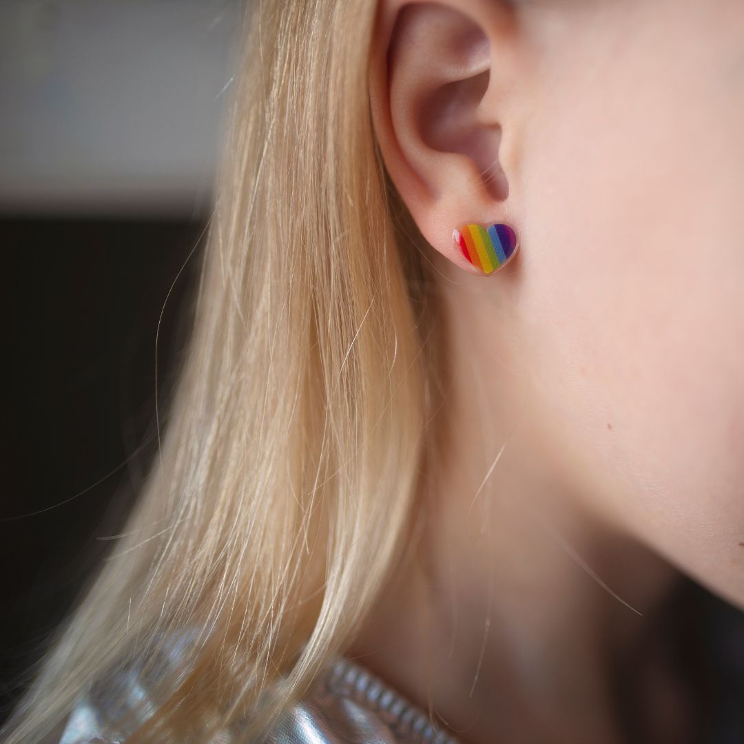 Een kind draagt een regenboog hart plakoorbel op het oor.