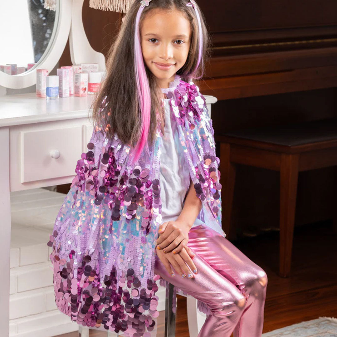 Een meisje draagt de Great Pretenders verkleedcape voor kinderen met paarse pailletten.