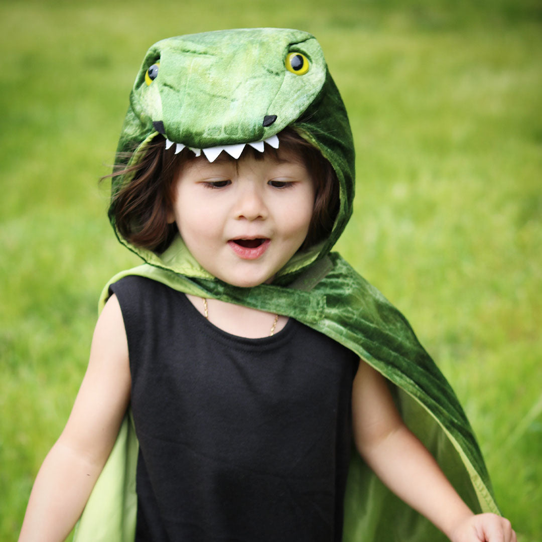 Detail van een kind met de capuchon van de groene dino T-Rex verkleedcape.
