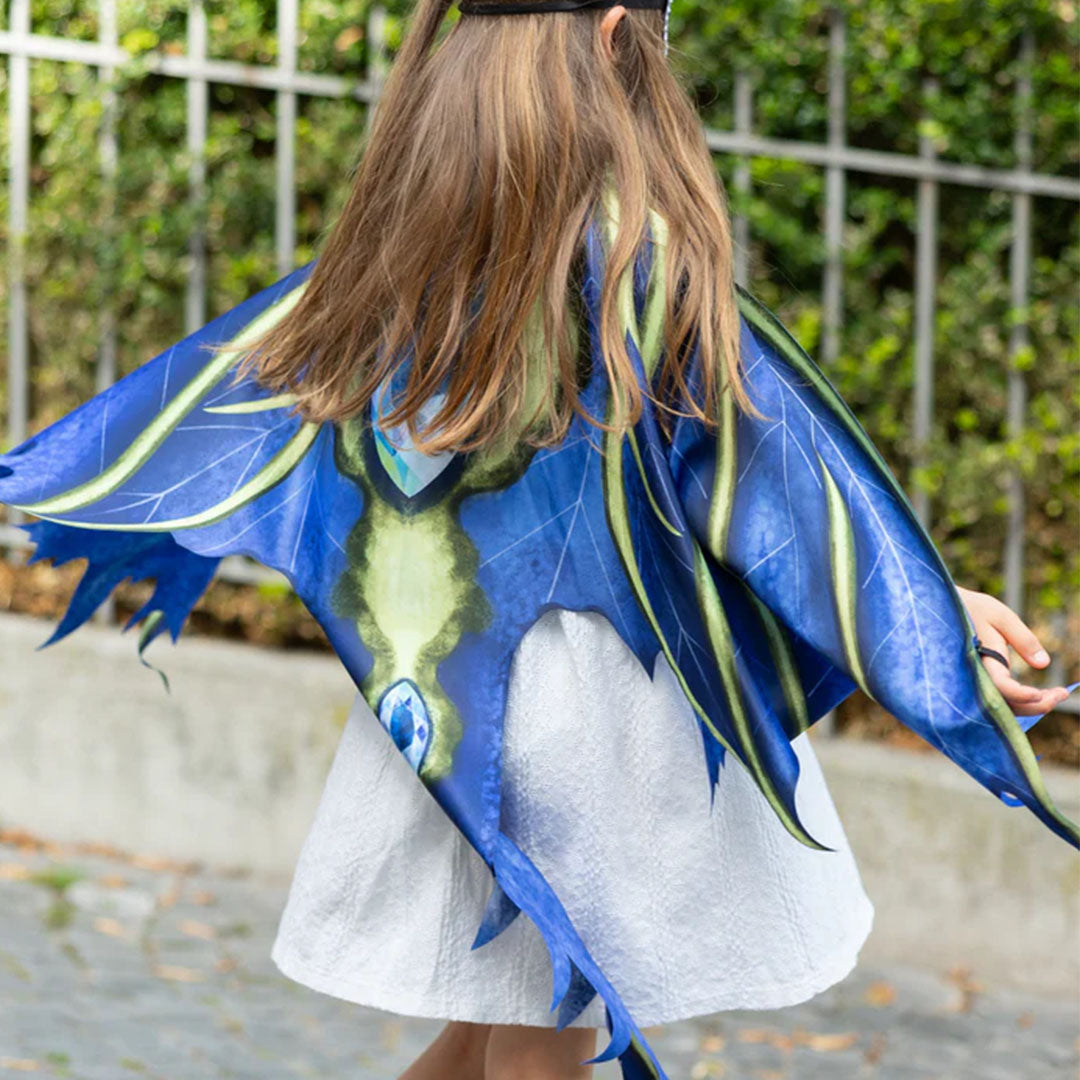Een kind draagt de blauwe draken verkleedcape met uitgespreide vleugels, van achteren gezien.