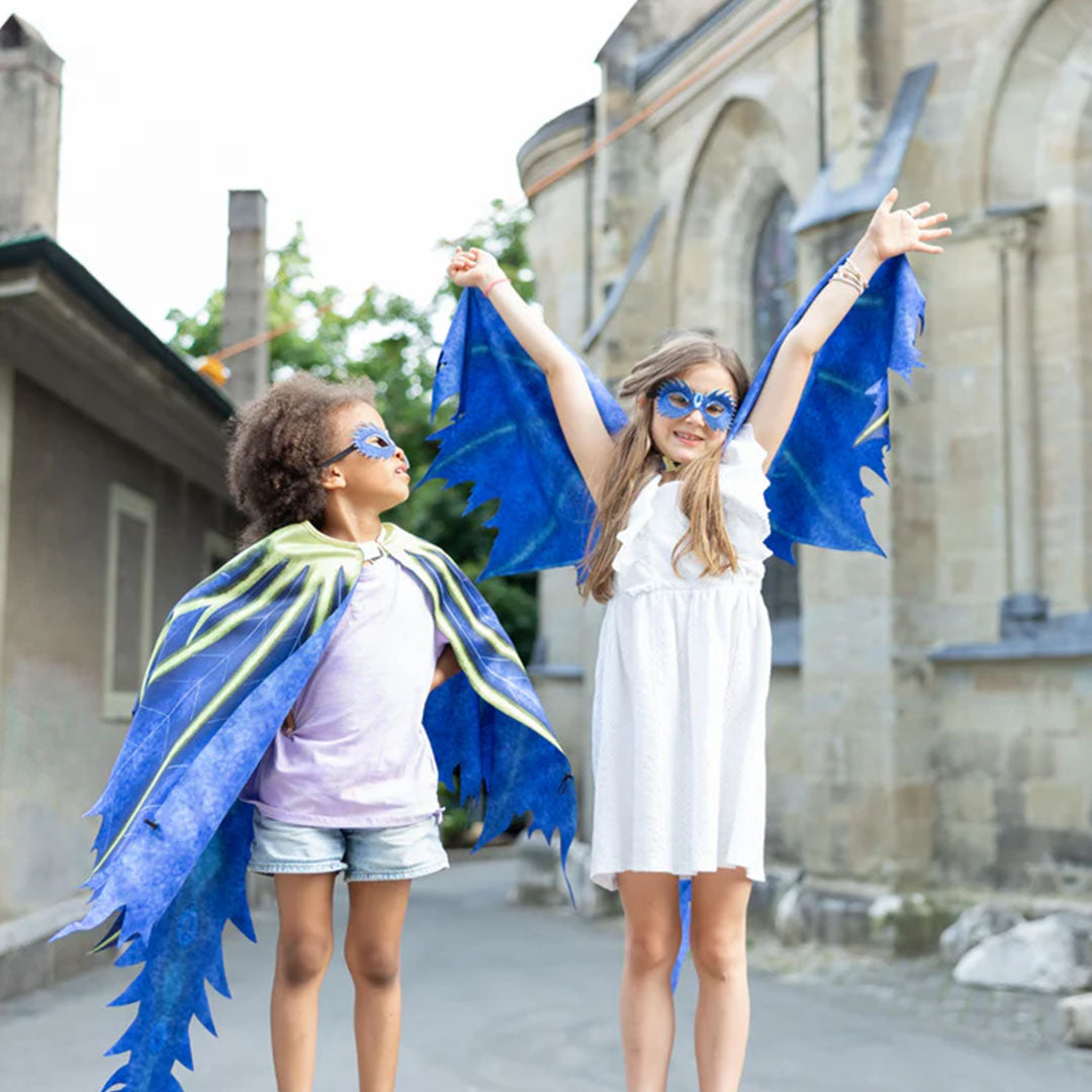 Twee kinderen dragen de blauwe draken verkleedcapes en maskers buiten voor een gebouw.