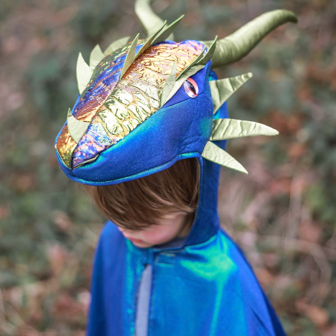 Detail van een kind dat de capuchon van de Great Pretenders verkleedcape draak emerald draagt, met de drakenkop en schubben duidelijk zichtbaar.