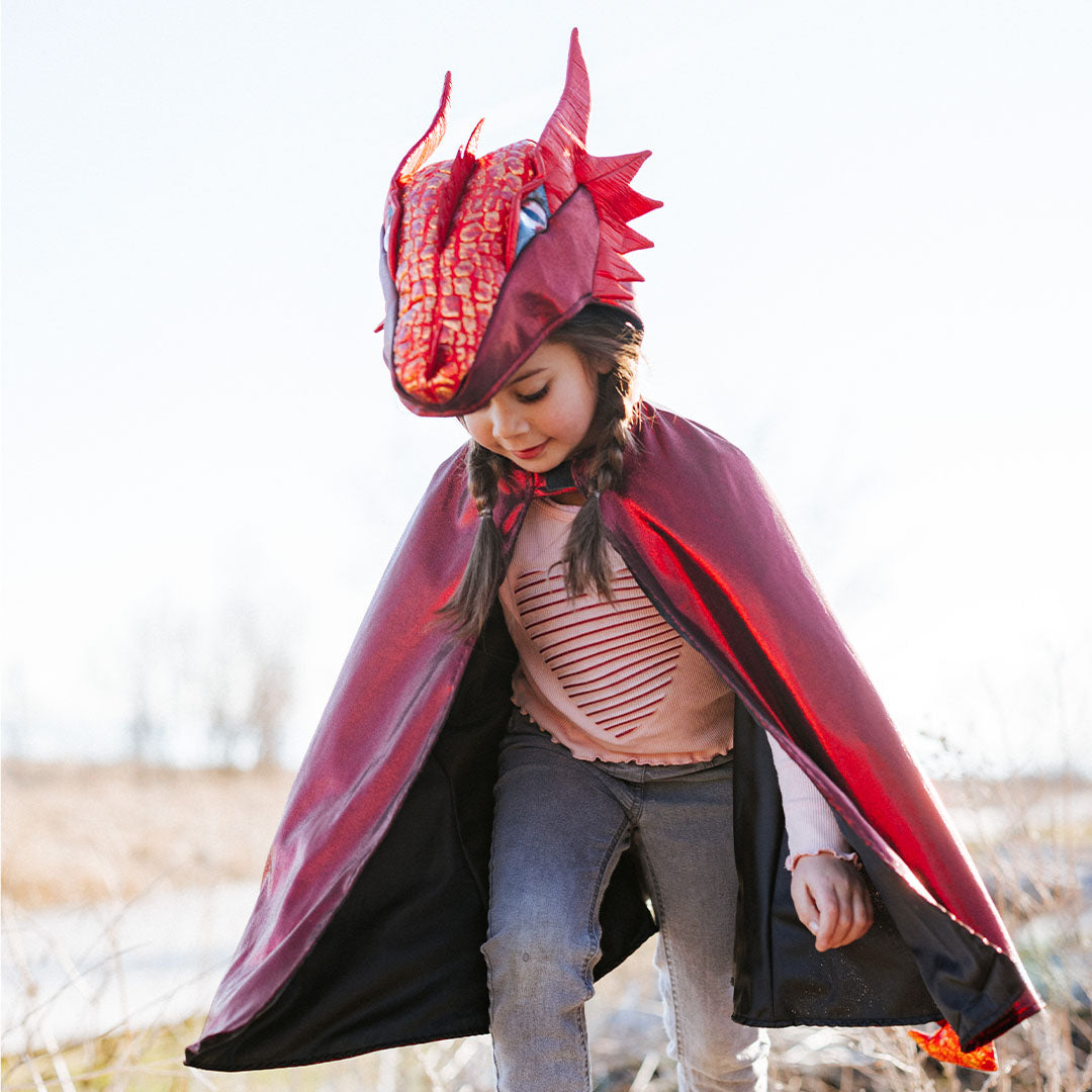 Een kind draagt de Great Pretenders rode draak verkleedcape buiten.