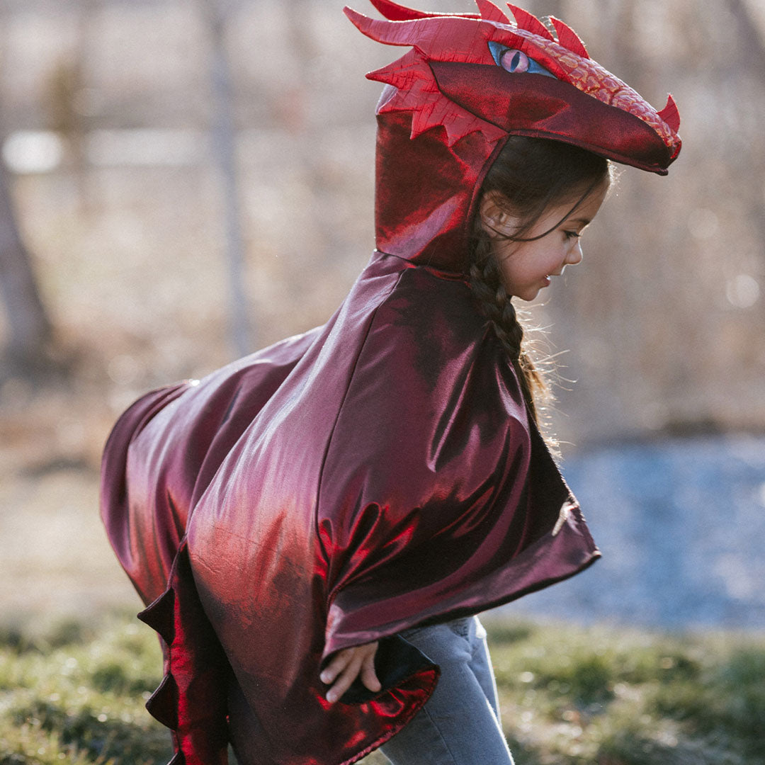 Zijaanzicht van een kind dat de rode draak verkleedcape draagt.