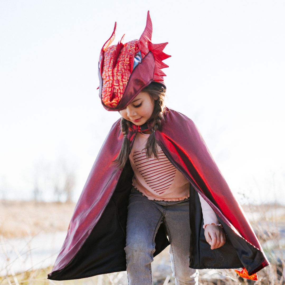 Een kind draagt de great pretenders rode metallic draken verkleedcape en loopt buiten.