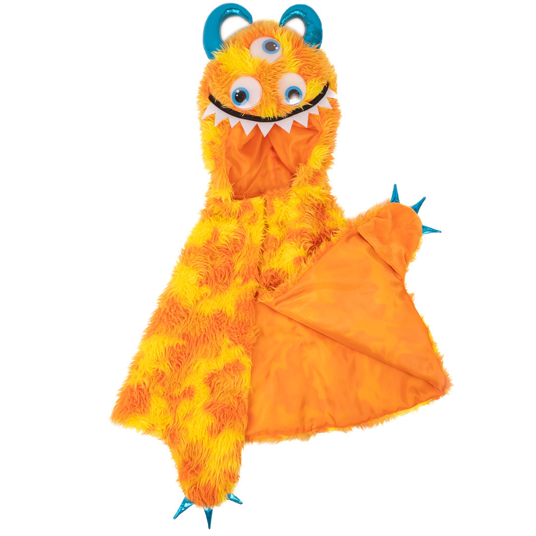 De great pretenders verkleedcape van pluche in de vorm van een oranje en gele monster, plat gelegd met de oranje voering zichtbaar.