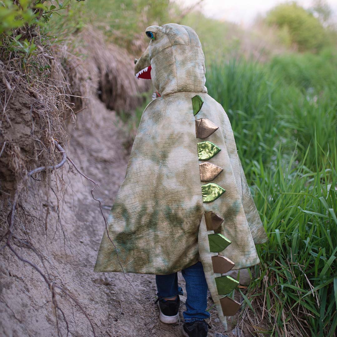 Kind van achteren gezien draagt de great pretenders T-Rex verkleedcape met stekels op de rug.