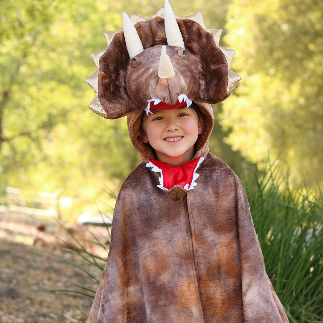 Een lachend kind draagt de triceratops verkleedcape en kijkt naar voren.