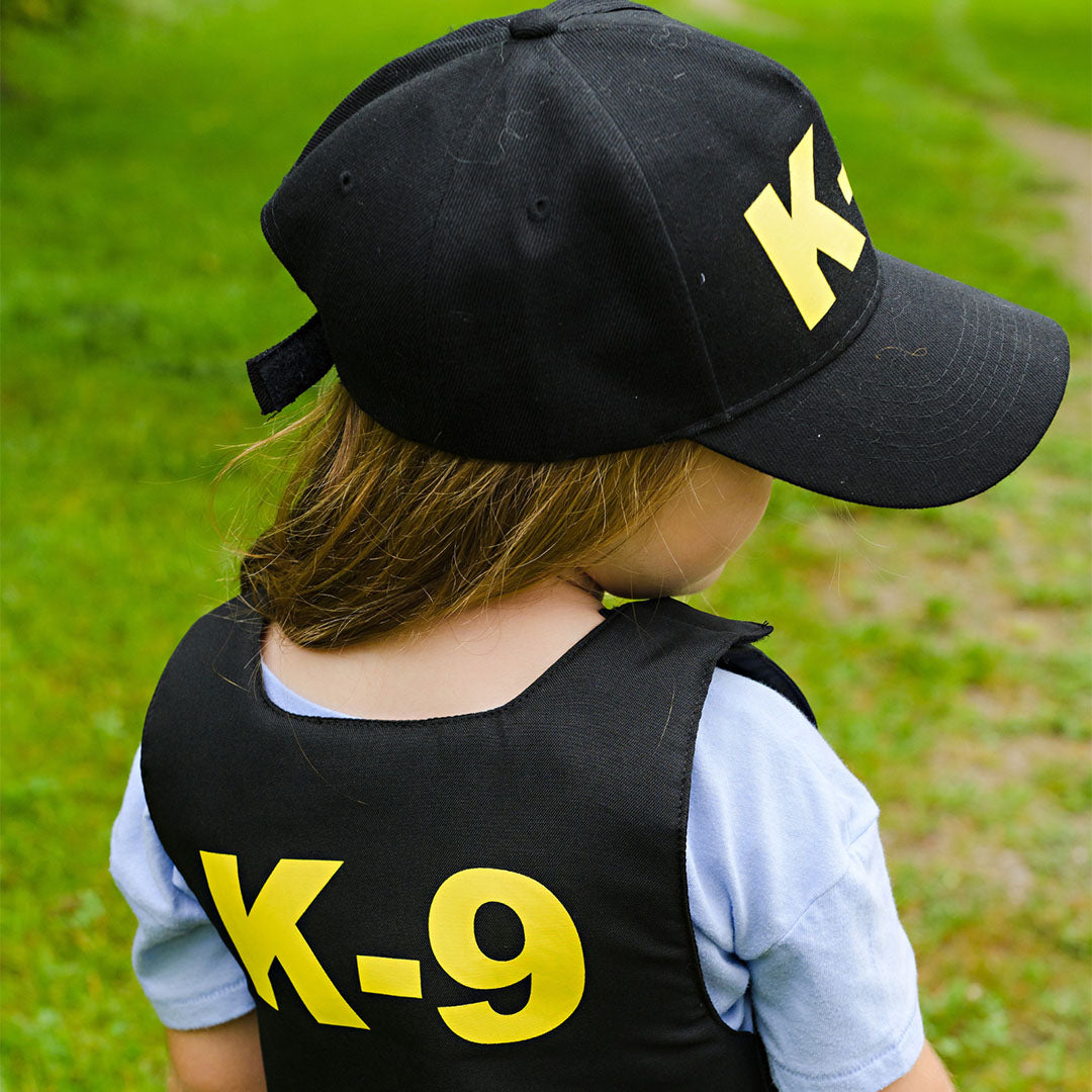 Achterkant van een meisje in K-9 politieagent verkleedkleding met 'K-9' op de pet en het vest.