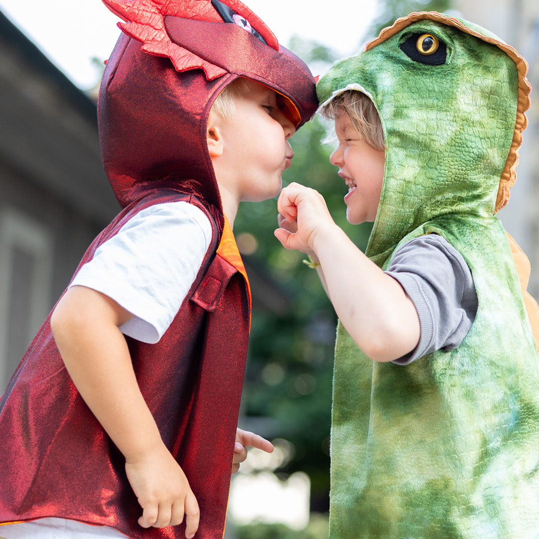 Twee lachende kinderen in een rood draken verkleedvest en een groen dinosaurus verkleedvest.