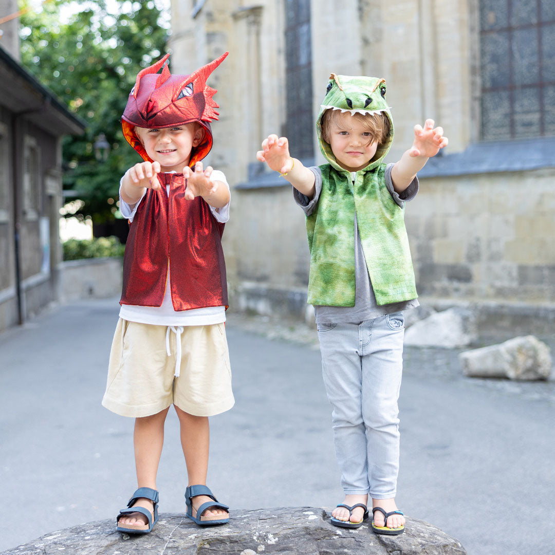 Twee kinderen, één in een rood Great Pretenders draken verkleedvest en één in een groen dinosaurus verkleedvest, staan met uitgestrekte armen.